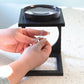 side view of the foldable magnifier in use while closing a necklace