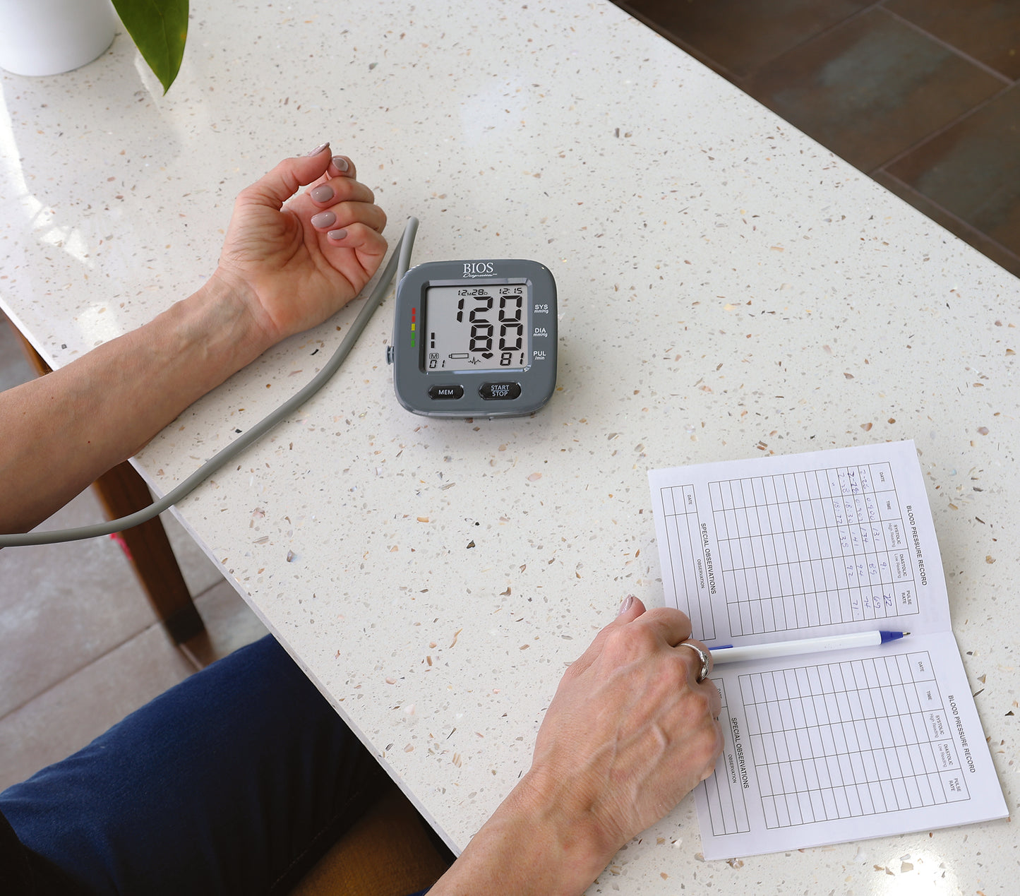 blood pressure monitor in action taking a reading, patients log book on the side